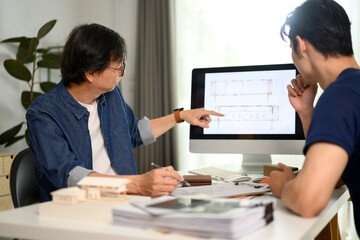 Professional architect man pointing on computer monitor discussing building plan design project with his client