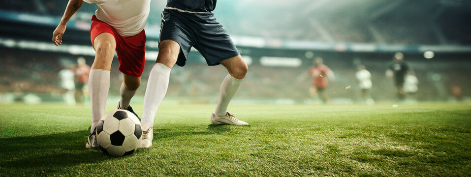 Dynamic image of male legs, football players in motion on filed dribbling ball, playing soccer at 3D stadium model with blurred background. Concept of professional sport, competition, tournament