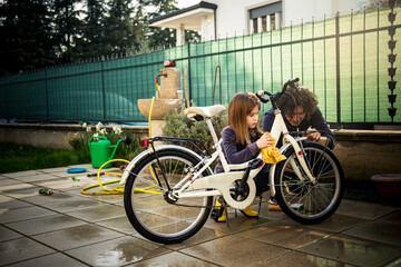 Caucasian father and schoolgirl daughter in the backyard cleaning her bike for springtime.