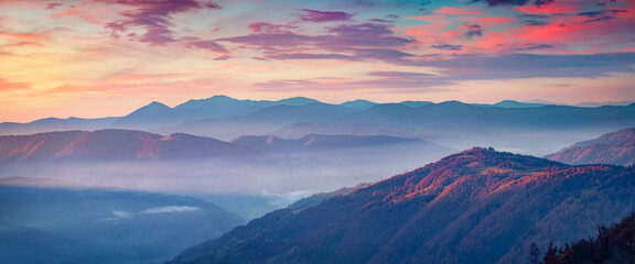 Long focus picture of misty rolling hills in Carpathian mountains. Splendid autumn sunrise on...