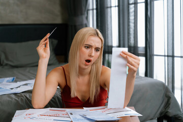 Stress worried young woman sit at table, as she pay bills online with credit card from financial...