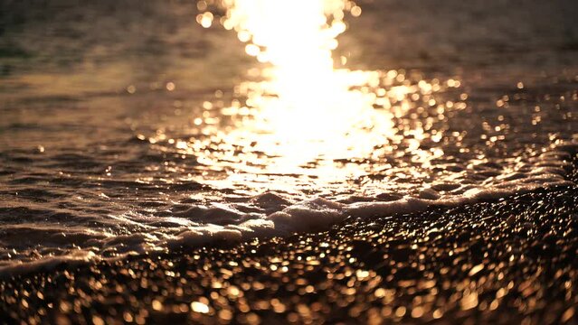 Abstract sea summer ocean sunset nature background. Small waves on golden water surface in motion blur with golden bokeh lights from sun. Holiday, vacation and recreation. Weather and climate change.
