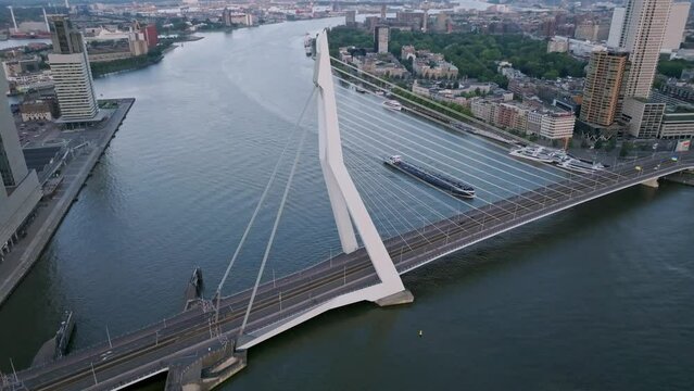 Tilting down drone shot boat passing underneath Erasmus bridge, Rotterdam