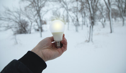 Male hand showing light bulb at winter.
