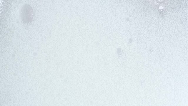 White soap suds flowing down window glass, close up. Taking a shower. Cleaning windows with cleaning disinfectant. Hygiene, disinfection, housework, household, cleanup, washing.
