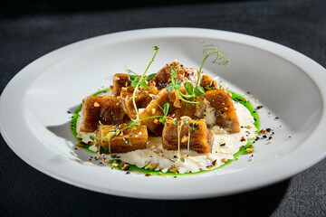 Crispy eggplant with stracciatella cheese and a drizzle of green sauce on a white plate, a closeup of a culinary delight