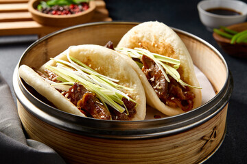 Elegant presentation of Peking duck Bao buns garnished with fresh green onions, in traditional...