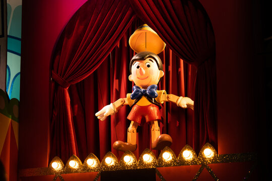 JAPAN - NOV 15, 2023: A charming wooden Pinocchio puppet standing on a theater stage with red curtains and glowing lights, evoking nostalgia and fairy tale magic at Tokyo Disney Land