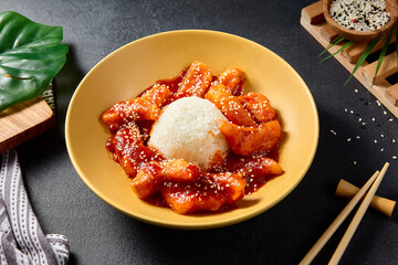 Sweet and sour fish fillet dish served with steamed rice; a classic Asian culinary delight on a black table setting