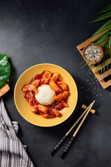 Top view of sweet and sour fish on a vibrant yellow plate, an Asian cuisine classic presented on a sleek black background