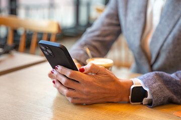 Unrecognizable Caucasian business woman using an app on her smartphone in a cafe