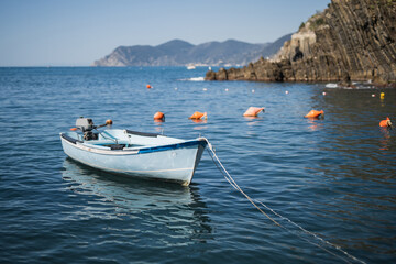Fototapeta premium A wooden fishing boat sways peacefully on clean, clear water in sunny, calm weather - a coastal idyll