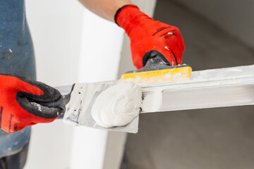 A professional builder levels the walls with putty - preparing the walls for painting and...