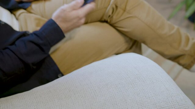 Young man sitting in an armchair, grabs his smartphone to look at it
