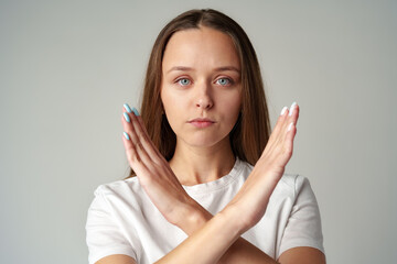 Young woman showing you crossed hands sign declining your request on gray background