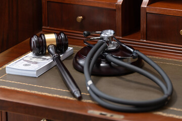 An image depicting a judge's gavel, a medical stethoscope, and a stack of US currency, highlighting the costly nature of legal and medical services. - Powered by Adobe