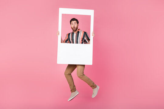 Full body length photo of jumping trampoline man holding astonished excited holding frame portrait isolated on pink color background