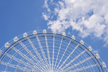 Part of ferris wheel in white color against summer blue sky