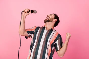 Cercles muraux Magasin de musique Photo of young funny man showman rock roll singer holding microphone raised fist up talented artist isolated on pink color background