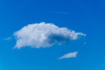 A lone white cloud on a blue sky and above them two airplanes flying and leaving steam smoke trail - obrazy, fototapety, plakaty