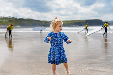 Little cute toddler girl at the Ballybunion surfer beach, having fun on with playing on west coast...