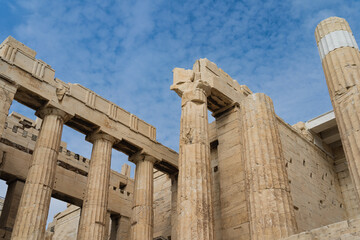 Columns in the Greek acropolis against a background of blue sky with clouds.