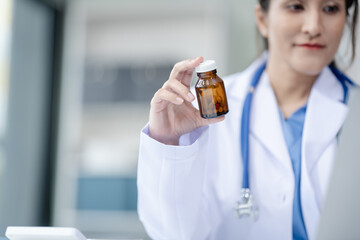 Portrait of mix race asian middle age female doctor in white lab coat and stethoscope while consult online in laptop. advice on good mental health management and medical treatment costs.