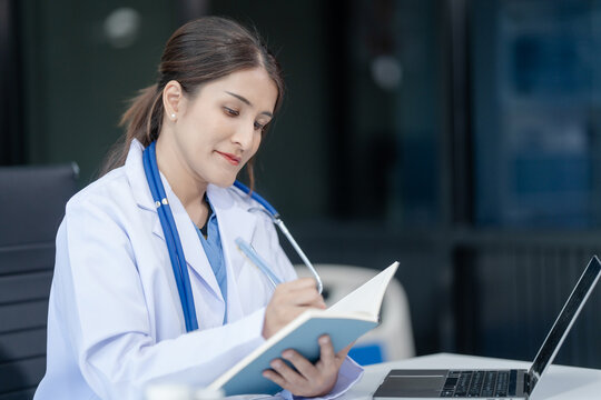 Portrait of mix race asian middle age female doctor in white lab coat and stethoscope while consult online in laptop. advice on good mental health management and medical treatment costs.