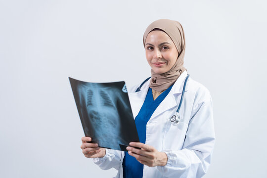 Asian Muslim doctor in hijab and scrubs headphones around her neck Stand confidently in the medical office, isolated on white background, holding x-ray film.