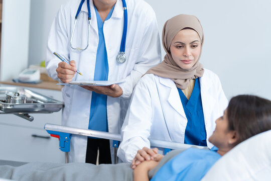 Two conficent doctor or specialist of kidney cancer talking together with female mix race patient on bed at medical ward, checkup, recovering after successful surgery concept.