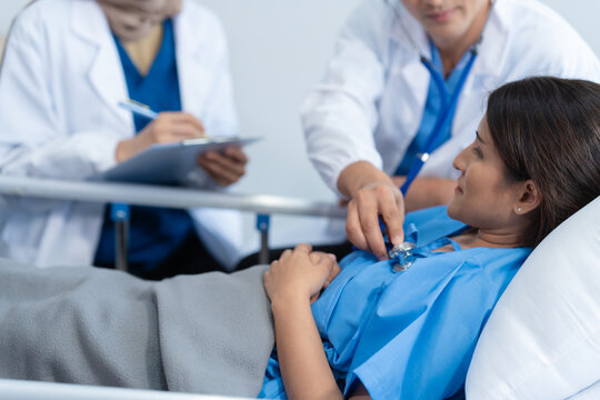 Two conficent doctor or specialist of kidney cancer talking together with female mix race patient on bed at medical ward, checkup, recovering after successful surgery concept.
