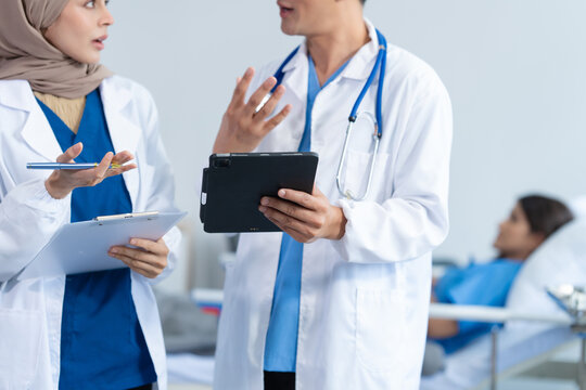 Two conficent doctor or specialist of kidney cancer talking together with female mix race patient on bed at medical ward, checkup, recovering after successful surgery concept.