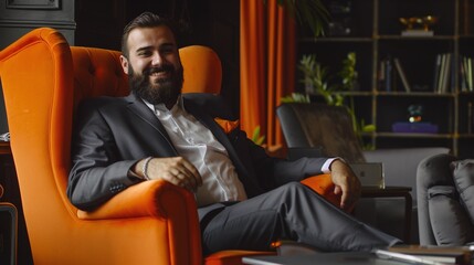 modern entrepreneur in a stylish business suit enjoying his success while working on a laptop in a luxury office with orange armchair - obrazy, fototapety, plakaty