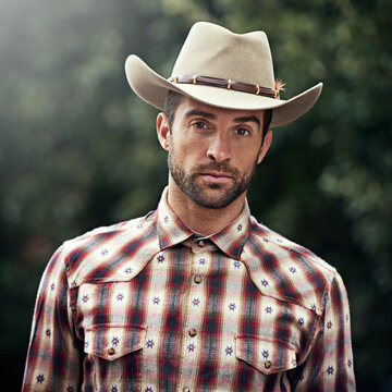 Man, portrait and outdoor cowboy outfit, western culture and countryside ranch in Texas. Male person, hat and flannel trend for farmer aesthetic, nature and plaid style by trees or outside bush