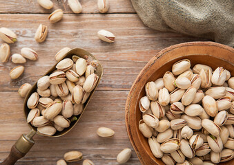 Salted pistachio nuts in wooden bowl plate with scoop on light background.Macro.