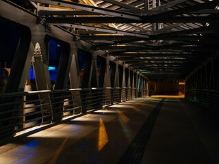 pedestrian bridge with metal structure in the city at night. Light and shadow