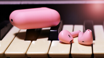 Pink bright headphones on piano keys, wireless technology