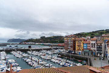 Panoramic view of the small harbour full of boats in the touristic coastal town of Bermeo on a cloudy day.