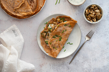 Homemade buckwheat crepes. Galettes Bretonnes with mushrooms on a light background. Traditional French cuisine.