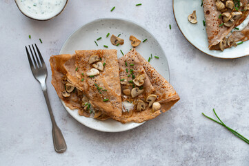 Homemade buckwheat crepes. Galettes Bretonnes with mushrooms on a light background. Traditional French cuisine.