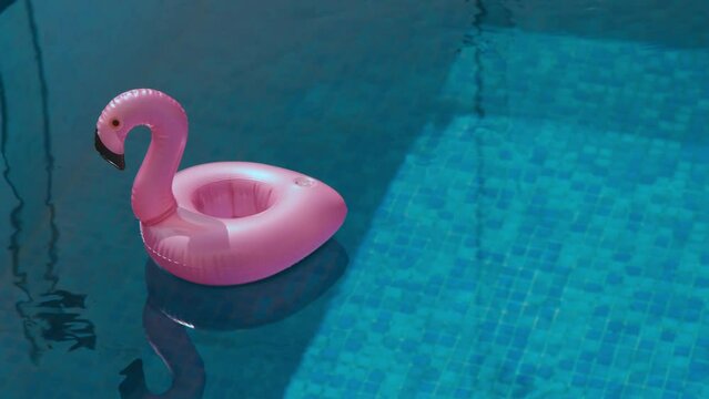 Pink pool float flamingo by blue water. Summer vacation. Pool party toy.
