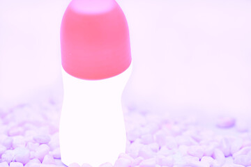 Pink top of glass roll deodorant bottle for body care on purple stones