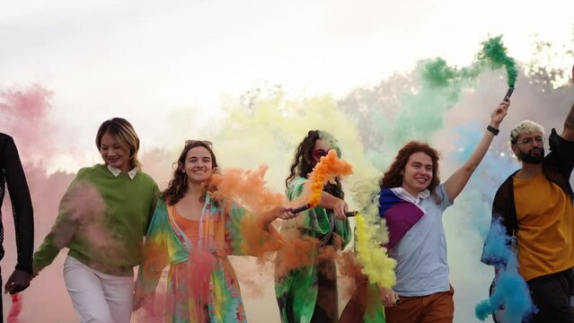 Diverse excited group young people walking, dancing and celebrating together gay pride day with rainbow colors smoke flares and flags outdoor. LGBT community and inclusive relations symbols in gen z