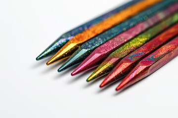 A close up of a line of vibrant Double Pointed knitting needles on a clean white surface, showcasing a mix of electric blue, magenta, and natural material accessories. Copy space
