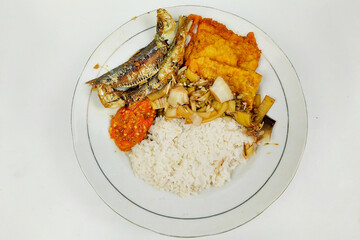 Rice mixed with fried fish and tempeh vegetables on a white plate, on the table