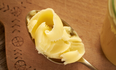Ghee or clarified butter on a metal spoon on a table