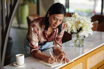 Elegant businesswoman having cup of coffee and writing in planner - 763967250