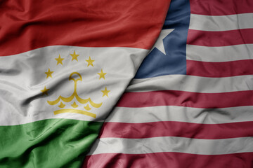 big waving national colorful flag of liberia and national flag of tajikistan.
