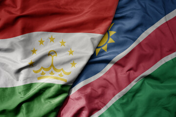 Fototapeta premium big waving national colorful flag of namibia and national flag of tajikistan.