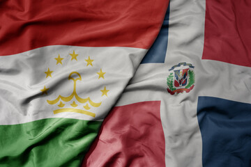 big waving national colorful flag of dominican republic and national flag of tajikistan.
